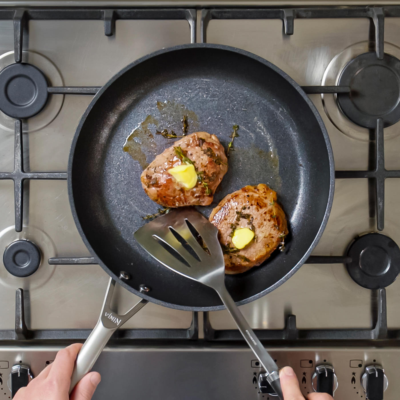 A person cooking two steak fillets in a Ninja frying pan